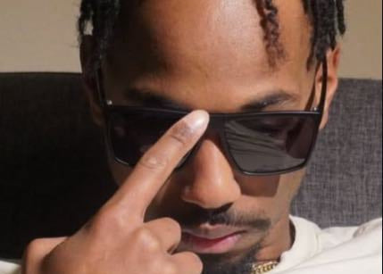 A pair of black-framed sunglasses with grey lenses displayed against a neutral background.